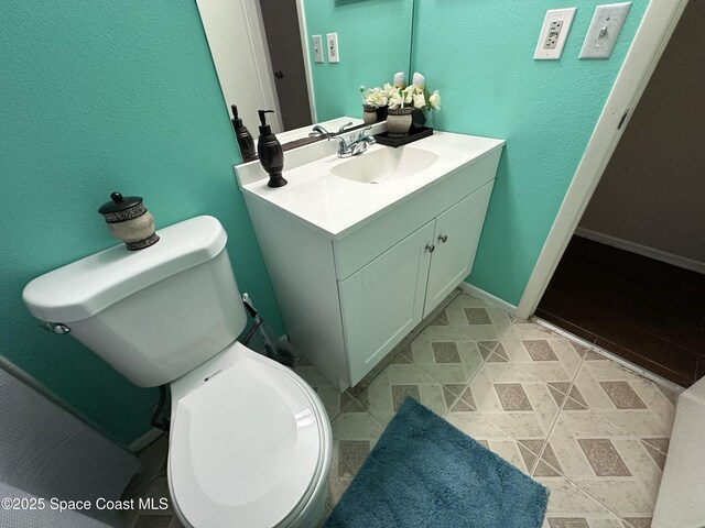 1021 Abada Ct NE Unit 106, Palm Bay, FL 32905 - bathroom featuring toilet, vanity, baseboards, and a textured wall