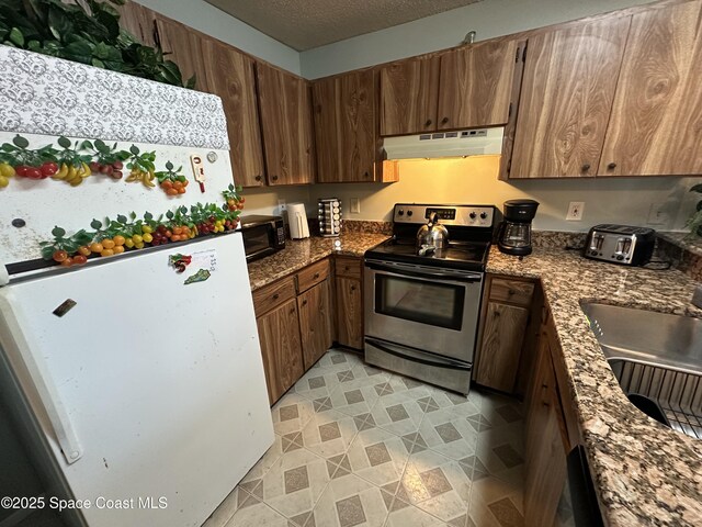 1021 Abada Ct NE Unit 106, Palm Bay, FL 32905 - kitchen with stainless steel electric stove, freestanding refrigerator, under cabinet range hood, a sink, and black microwave