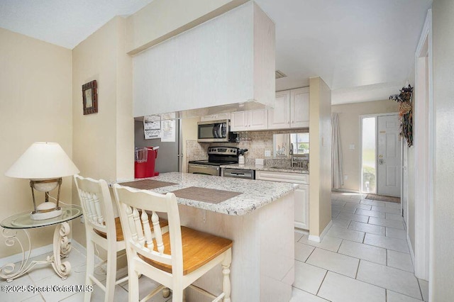 635 Seaport Blvd Unit T257, Cape Canaveral, FL 32920 - kitchen featuring appliances with stainless steel finishes, a kitchen bar, backsplash, baseboards, and light stone counters