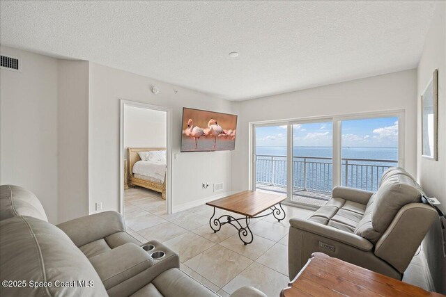 1825 Riverside Dr Unit 205, Titusville, FL 32780 - living room featuring a water view, a textured ceiling, light tile patterned flooring, and baseboards