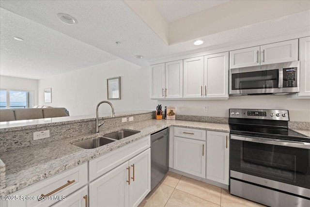 1825 Riverside Dr Unit 205, Titusville, FL 32780 - kitchen featuring stainless steel appliances, a sink, white cabinets, light stone countertops, and light tile patterned flooring