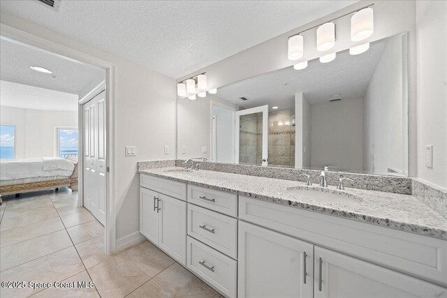 1825 Riverside Dr Unit 205, Titusville, FL 32780 - ensuite bathroom with double vanity, a textured ceiling, tiled shower, tile patterned flooring, and baseboards