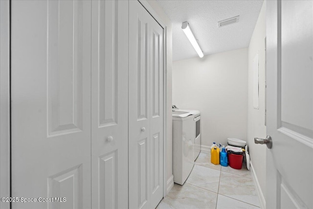 1825 Riverside Dr Unit 205, Titusville, FL 32780 - laundry area featuring independent washer and dryer, light marble finish floors, a textured ceiling, and baseboards