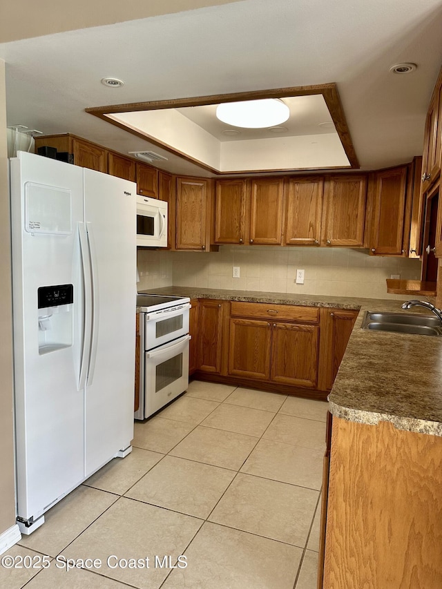 115 Angelo Rd SE, Palm Bay, FL 32909 - kitchen with white appliances, a tray ceiling, a sink, brown cabinetry, and light tile patterned floors