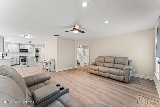 2225 Royal Oaks Dr, Rockledge, FL 32955 - living room featuring baseboards, ceiling fan, stairs, light wood finished floors, and recessed lighting