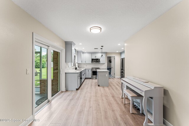 2225 Royal Oaks Dr, Rockledge, FL 32955 - kitchen featuring stainless steel appliances, gray cabinetry, light countertops, light wood finished floors, and a kitchen island