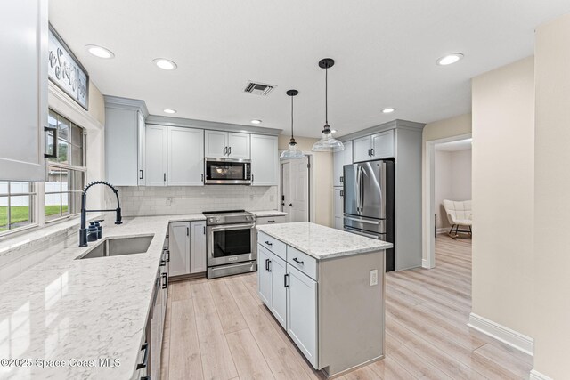 2225 Royal Oaks Dr, Rockledge, FL 32955 - kitchen featuring stainless steel appliances, a sink, backsplash, gray cabinetry, and a center island