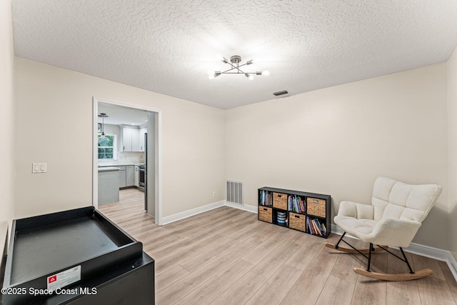 2225 Royal Oaks Dr, Rockledge, FL 32955 - living area featuring light wood finished floors, a textured ceiling, and baseboards