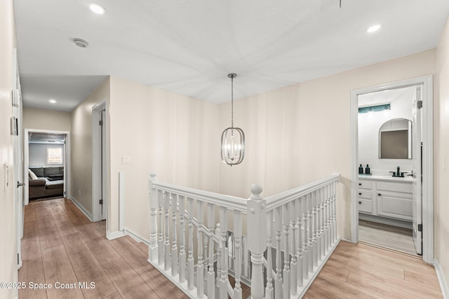 2225 Royal Oaks Dr, Rockledge, FL 32955 - hall with an upstairs landing, light wood-style floors, a chandelier, baseboards, and a sink