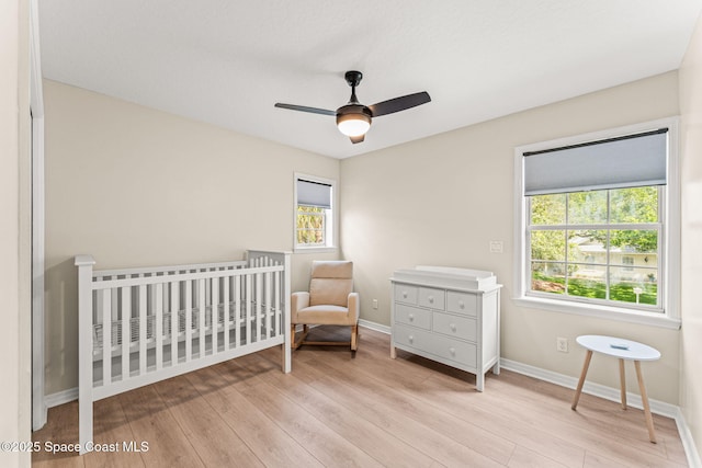 2225 Royal Oaks Dr, Rockledge, FL 32955 - bedroom with light wood-type flooring, baseboards, a crib, and ceiling fan