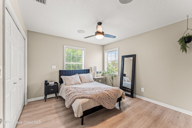 2225 Royal Oaks Dr, Rockledge, FL 32955 - bedroom with light wood-style flooring, baseboards, a closet, a ceiling fan, and a textured ceiling