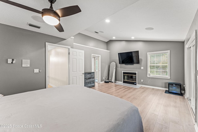 2225 Royal Oaks Dr, Rockledge, FL 32955 - bedroom featuring vaulted ceiling, light wood finished floors, baseboards, a fireplace with flush hearth, and a ceiling fan