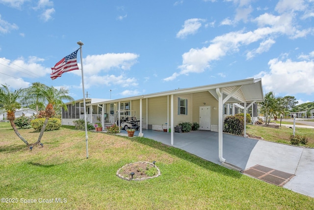 7685 Fox Hunter Cir, Micco, FL 32976 - view of front of property with driveway, an attached carport, a front lawn, and a sunroom