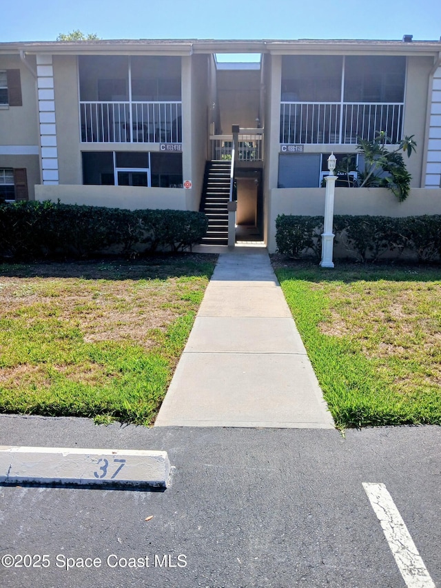 1641 Sunny Brook Ln NE Unit C110, Palm Bay, FL 32905 - view of front facade with stairs, a front yard, and stucco siding
