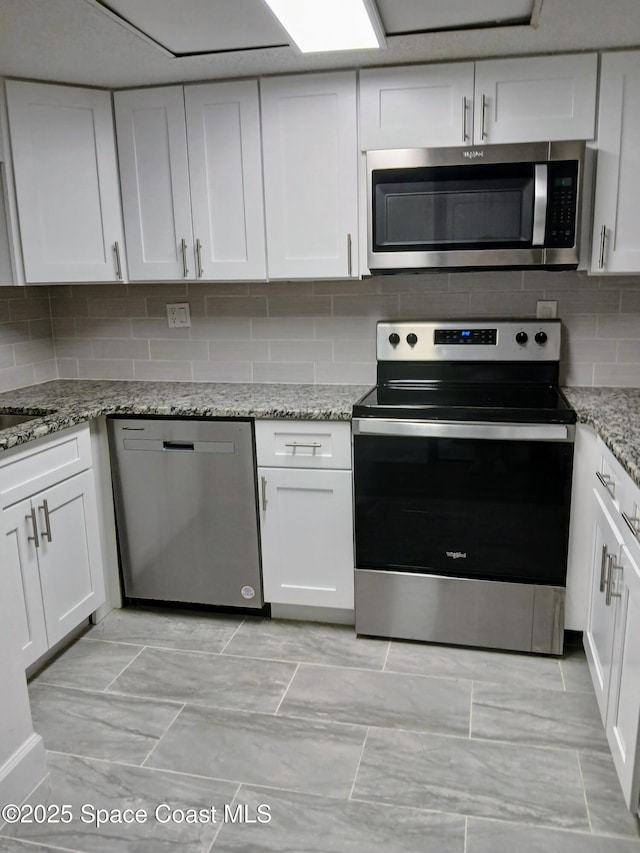 1641 Sunny Brook Ln NE Unit C110, Palm Bay, FL 32905 - kitchen featuring stainless steel appliances, white cabinets, decorative backsplash, light stone counters, and light marble finish flooring