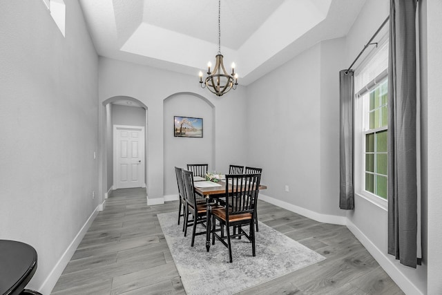 382 Eldron Blvd NE, Palm Bay, FL 32907 - dining space with arched walkways, healthy amount of natural light, a raised ceiling, and light wood finished floors