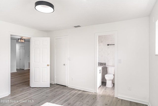 2885 Fountainhead Blvd, Melbourne, FL 32935 - unfurnished bedroom featuring light wood-style flooring, a chandelier, and connected bathroom
