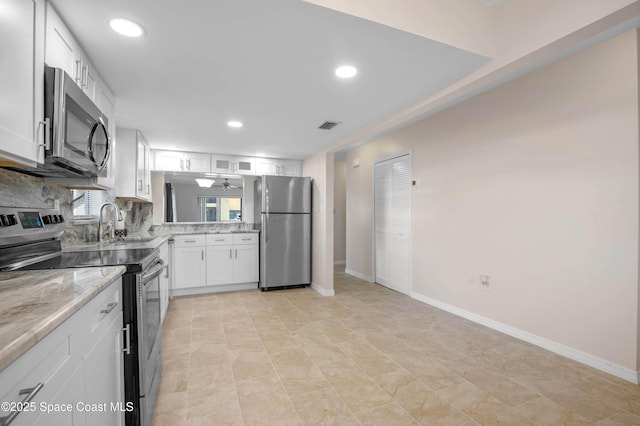 5630 N Banana River Blvd Unit 1, Cocoa Beach, FL 32931 - kitchen with stainless steel appliances, a sink, light stone countertops, white cabinets, and backsplash