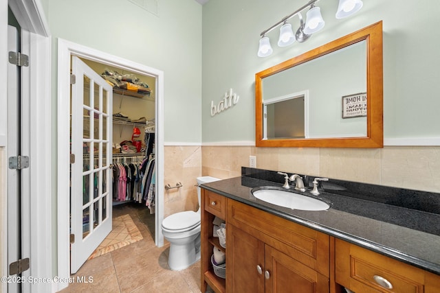 1398 Stuttgart Ave NW, Palm Bay, FL 32907 - bathroom featuring vanity, toilet, tile patterned flooring, tile walls, and wainscoting