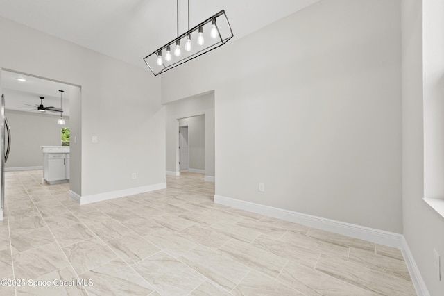 8286 100th Ave, Vero Beach, FL 32967 - unfurnished dining area with a ceiling fan, baseboards, a chandelier, and a towering ceiling