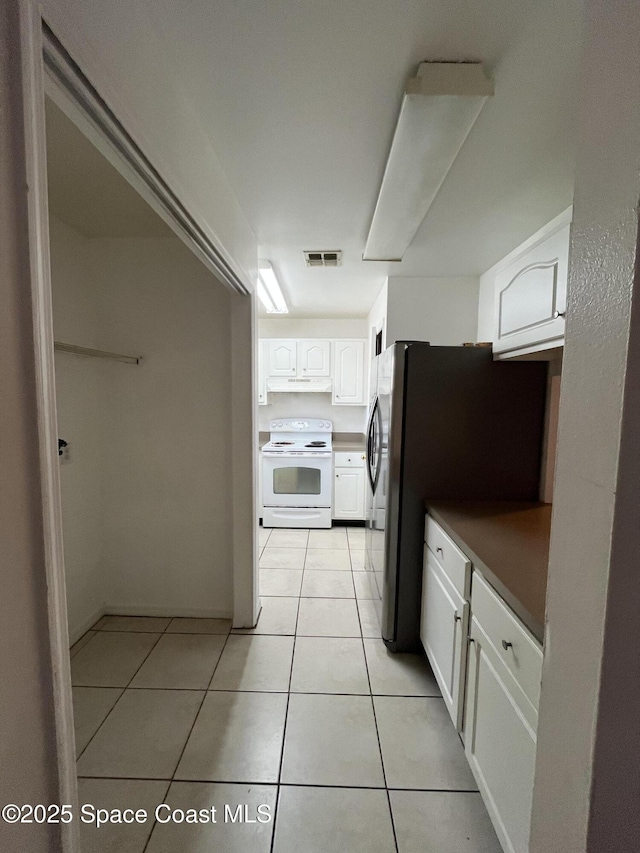 110 Summer Pl Unit 4, Merritt Island, FL 32953 - kitchen with white electric range oven, white cabinetry, light tile patterned flooring, under cabinet range hood, and freestanding refrigerator