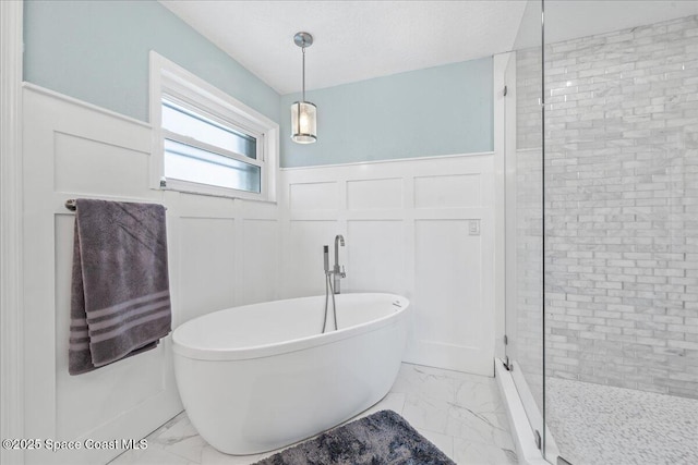 912 Hialeah St, Rockledge, FL 32955 - bathroom with marble look tile flooring, a decorative wall, a wainscoted wall, a freestanding bath, and a shower stall