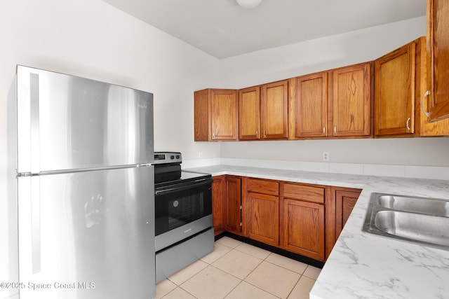 418 N Fiske Blvd, Cocoa, FL 32922 - kitchen with appliances with stainless steel finishes, brown cabinets, light tile patterned floors, and light stone countertops