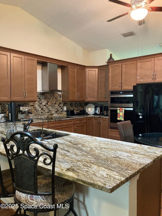 971 Sabal Grove Dr, Rockledge, FL 32955 - kitchen with black appliances, wall chimney range hood, a breakfast bar area, ceiling fan, and decorative backsplash