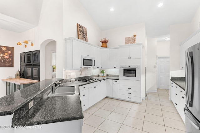 1172 Vestavia Cir, Melbourne, FL 32940 - kitchen with stainless steel appliances, a sink, arched walkways, a high ceiling, and light tile patterned flooring