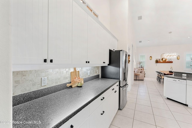 1172 Vestavia Cir, Melbourne, FL 32940 - kitchen with dishwasher, dark countertops, stainless steel fridge, white cabinets, and a towering ceiling