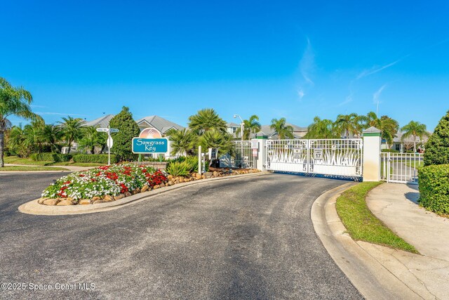 1172 Vestavia Cir, Melbourne, FL 32940 - view of asphalt street with a gate, curbs, sidewalks, street lights, and a gated entry