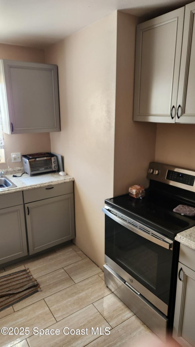 2327 Sadler Ln, Melbourne, FL 32935 - kitchen with stainless steel range with electric cooktop, gray cabinets, light countertops, a sink, and wood tiled floors