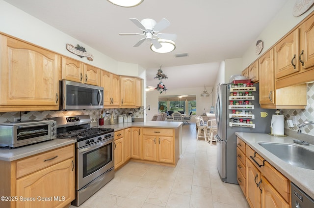 960 Mayflower Ave, Melbourne, FL 32940 - kitchen featuring appliances with stainless steel finishes, a sink, a ceiling fan, tasteful backsplash, and a peninsula