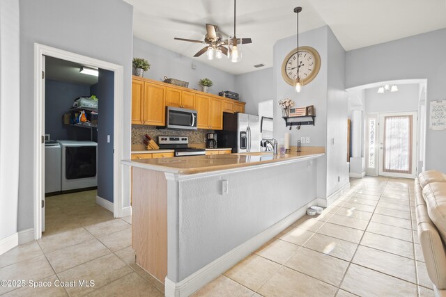 2922 Brandywine Cir, Titusville, FL 32796 - kitchen featuring stainless steel appliances, light tile patterned floors, washer and clothes dryer, a ceiling fan, and tasteful backsplash