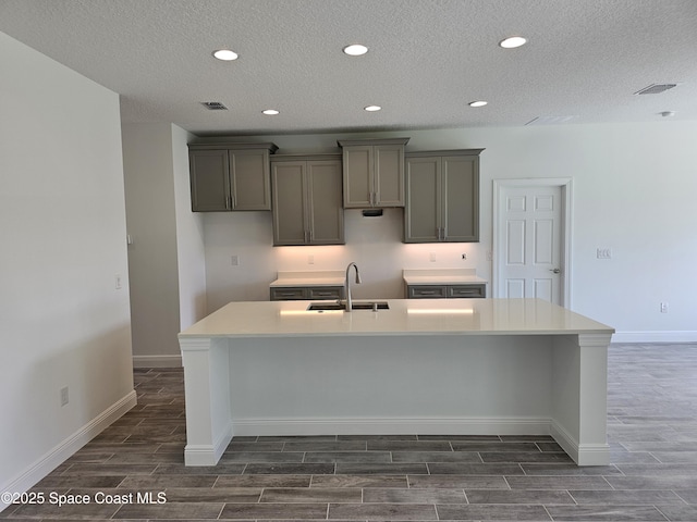 2999 Gaffney Ave SE, Palm Bay, FL 32909 - kitchen with wood tiled floors, a large island with sink, recessed lighting, gray cabinetry, and a textured ceiling