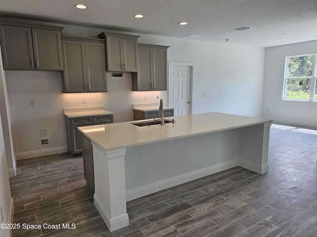 2999 Gaffney Ave SE, Palm Bay, FL 32909 - kitchen featuring wood tiled floors, a kitchen island with sink, a textured ceiling, gray cabinetry, and recessed lighting