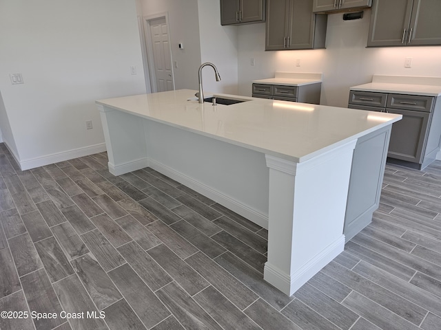 2999 Gaffney Ave SE, Palm Bay, FL 32909 - kitchen with wood tiled floors, an island with sink, and gray cabinets
