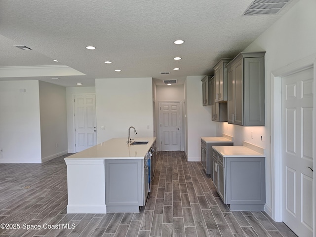 2999 Gaffney Ave SE, Palm Bay, FL 32909 - kitchen featuring a textured ceiling, wood finished floors, gray cabinets, an island with sink, and recessed lighting