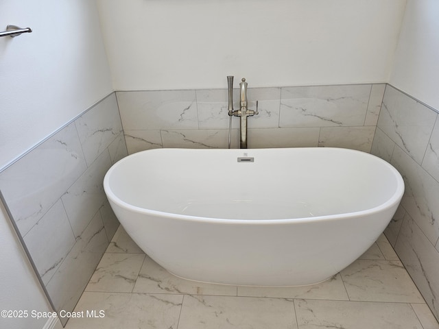 2999 Gaffney Ave SE, Palm Bay, FL 32909 - bathroom featuring tile walls, marble look tiles, a soaking tub, and wainscoting