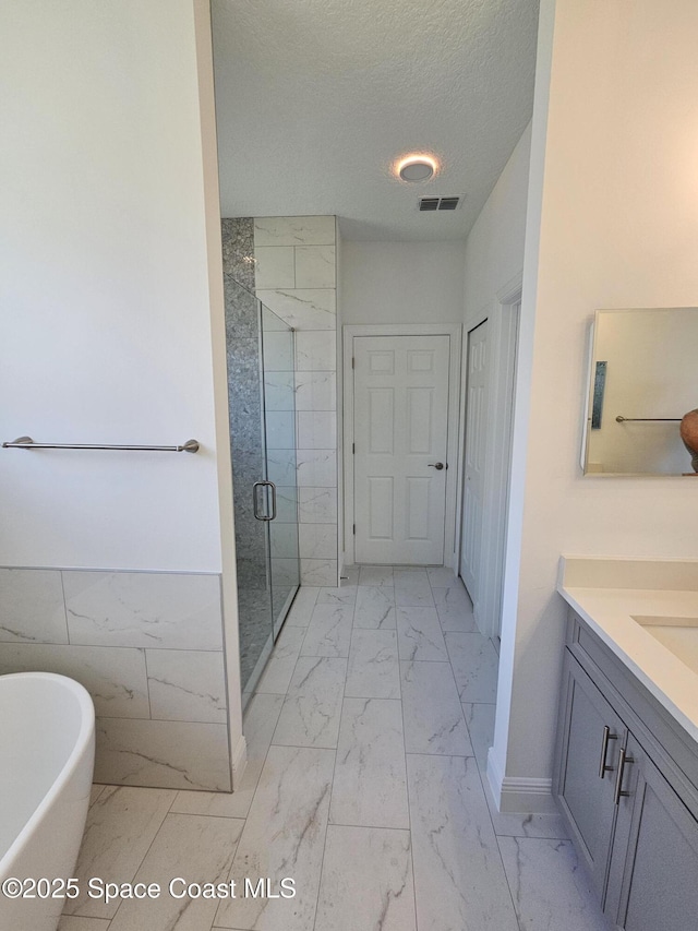2999 Gaffney Ave SE, Palm Bay, FL 32909 - full bath with marble finish floors, vanity, a shower stall, a freestanding tub, and a textured ceiling