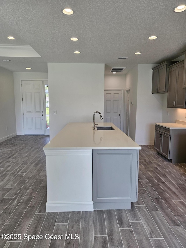 2999 Gaffney Ave SE, Palm Bay, FL 32909 - kitchen featuring wood finish floors, a textured ceiling, recessed lighting, an island with sink, and light countertops