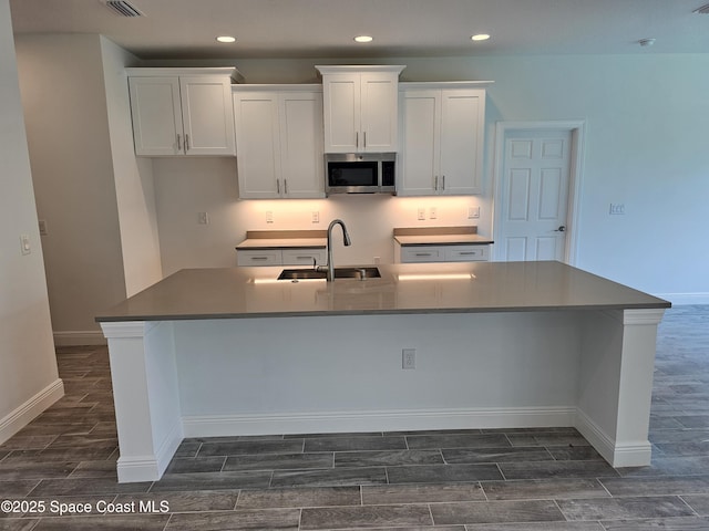 431 Falls Church St SW, Palm Bay, FL 32908 - kitchen featuring stainless steel microwave, wood tiled floors, recessed lighting, white cabinets, and a spacious island