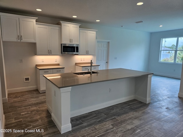 431 Falls Church St SW, Palm Bay, FL 32908 - kitchen featuring stainless steel microwave, dark wood-type flooring, white cabinetry, an island with sink, and recessed lighting