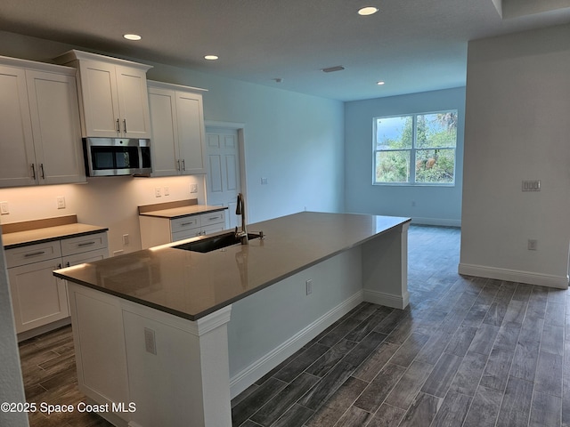431 Falls Church St SW, Palm Bay, FL 32908 - kitchen with stainless steel microwave, dark wood finished floors, an island with sink, white cabinetry, and recessed lighting