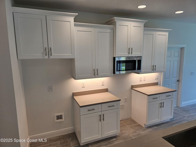 431 Falls Church St SW, Palm Bay, FL 32908 - kitchen with stainless steel microwave, wood finish floors, recessed lighting, white cabinetry, and light countertops