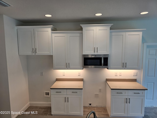 431 Falls Church St SW, Palm Bay, FL 32908 - kitchen with stainless steel microwave, wood tiled floors, recessed lighting, white cabinetry, and light countertops