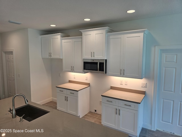 431 Falls Church St SW, Palm Bay, FL 32908 - kitchen with stainless steel microwave, light wood-style flooring, white cabinetry, and recessed lighting