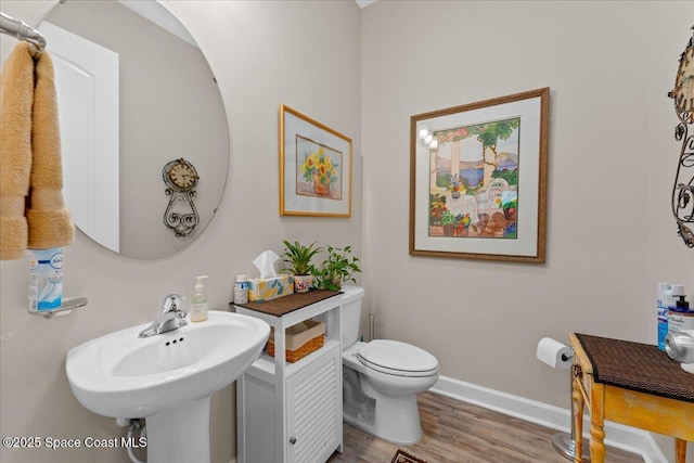 2889 Millennium Cir, Melbourne, FL 32940 - half bathroom featuring wood finished floors, toilet, baseboards, and a sink