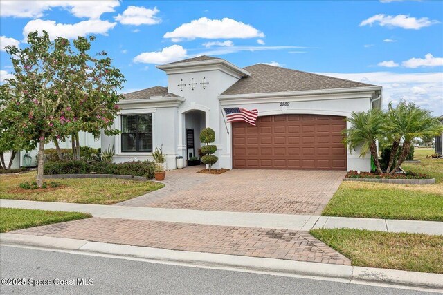 2889 Millennium Cir, Melbourne, FL 32940 - view of front of property featuring a garage, decorative driveway, stucco siding, and a front yard