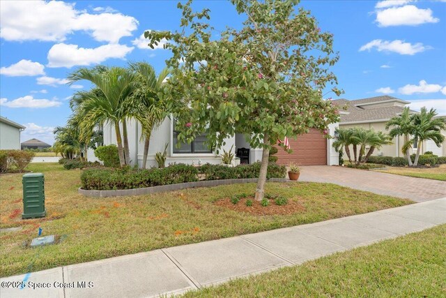 2889 Millennium Cir, Melbourne, FL 32940 - obstructed view of property featuring decorative driveway, a garage, a front lawn, and stucco siding
